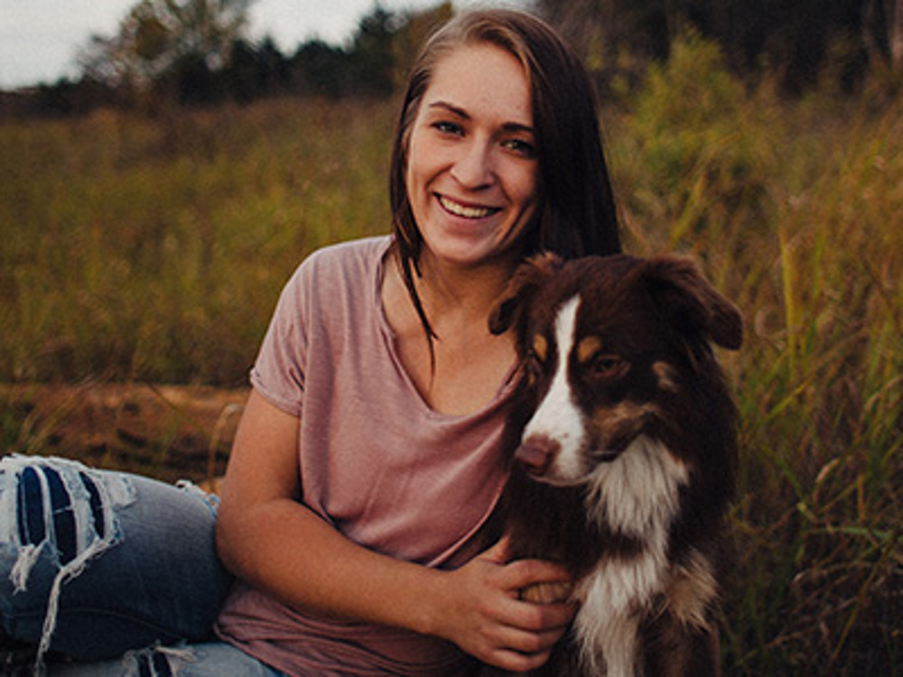 Woman sitting outside on grass with her dog