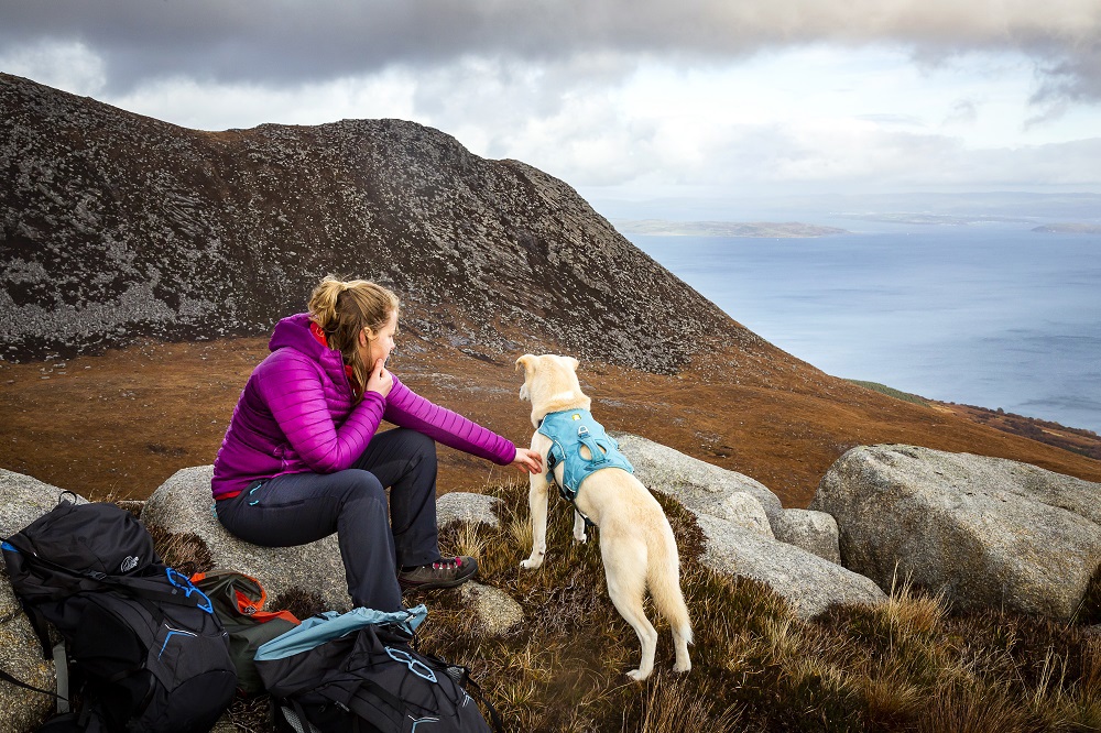 Girl sat with dog near sea area